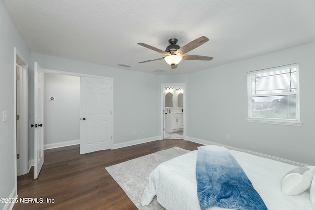 bedroom featuring visible vents, baseboards, connected bathroom, dark wood-style flooring, and a textured ceiling