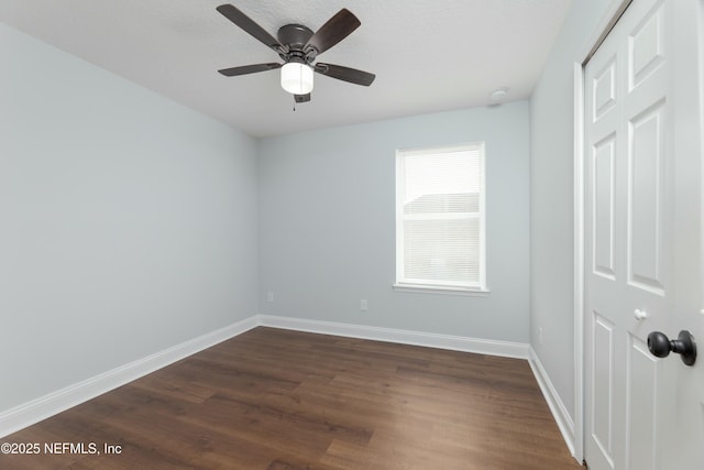 empty room featuring ceiling fan, baseboards, and dark wood-style flooring