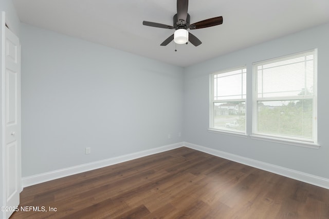 unfurnished room featuring dark wood-style floors, ceiling fan, and baseboards