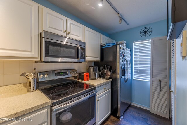 kitchen featuring rail lighting, white cabinetry, stainless steel appliances, dark hardwood / wood-style flooring, and decorative backsplash