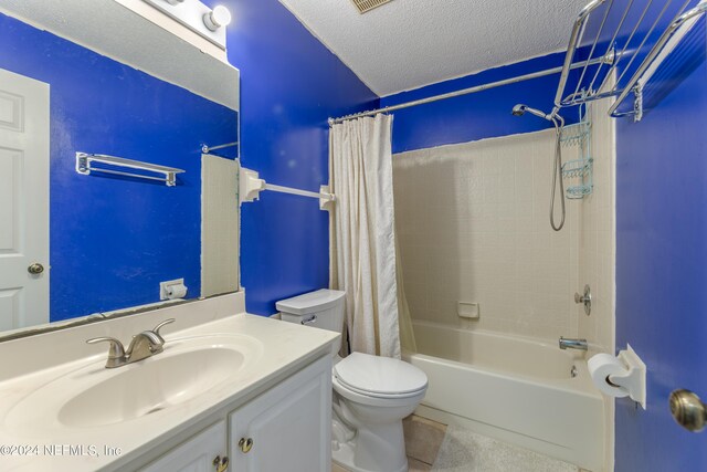 full bathroom with shower / bath combo with shower curtain, vanity, a textured ceiling, toilet, and tile patterned floors