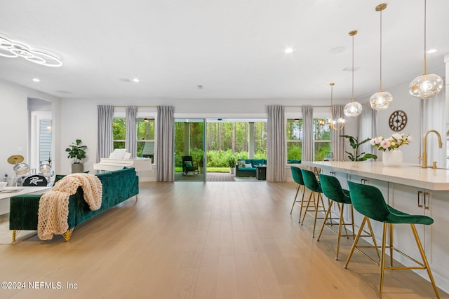 living room with light hardwood / wood-style floors, sink, and a chandelier