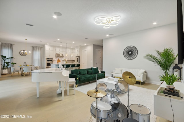 living room with a notable chandelier, light hardwood / wood-style floors, and a textured ceiling