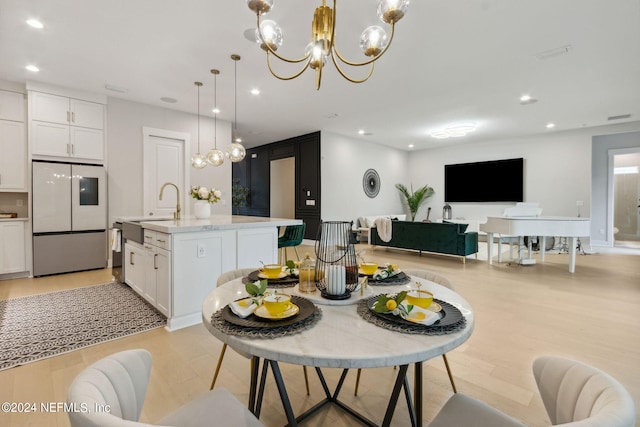 dining area featuring an inviting chandelier, light hardwood / wood-style floors, and sink