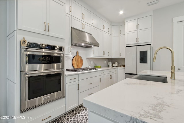 kitchen with decorative backsplash, white cabinetry, light stone countertops, stainless steel appliances, and sink