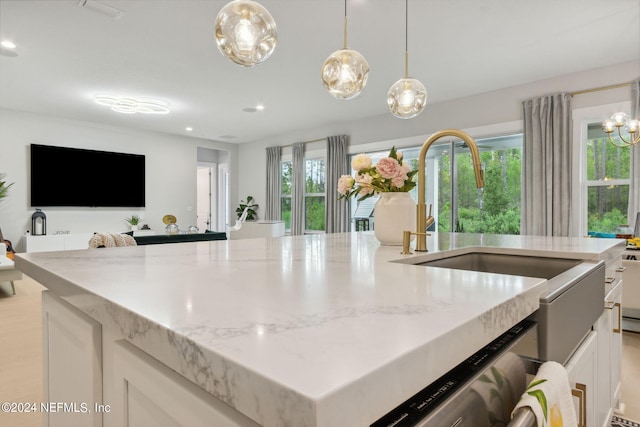 kitchen with light stone countertops, white cabinetry, and a healthy amount of sunlight