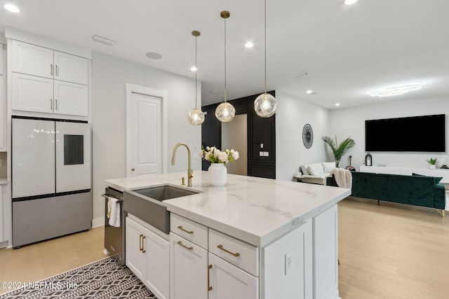 kitchen with hanging light fixtures, white cabinetry, light stone counters, light hardwood / wood-style flooring, and refrigerator