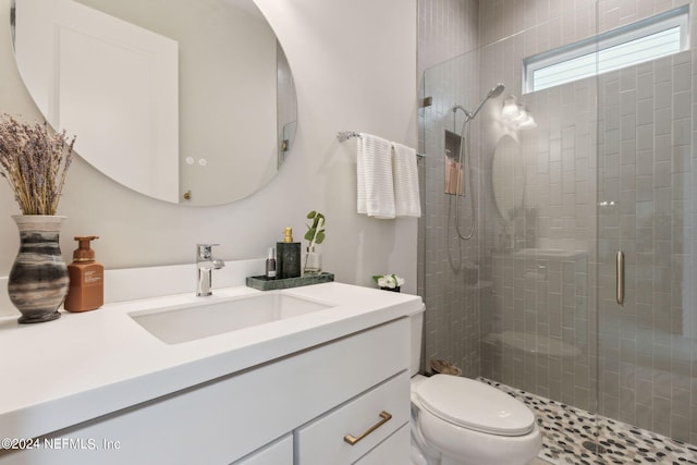 bathroom with walk in shower, vanity, and toilet