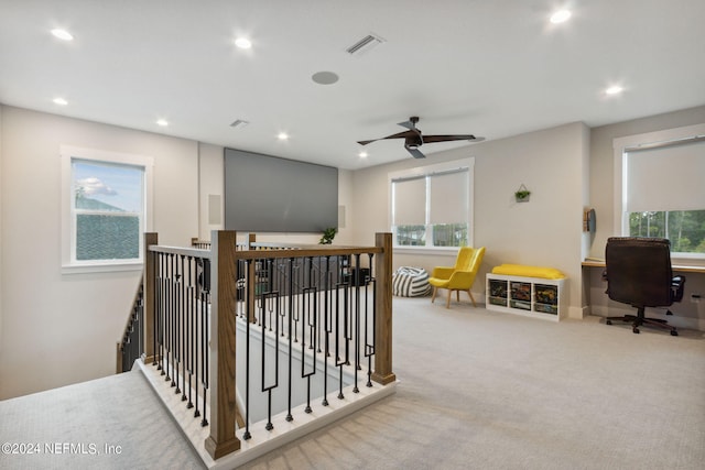 hall featuring light colored carpet and plenty of natural light