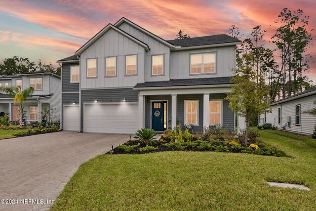 view of front of house featuring a yard, a porch, and a garage