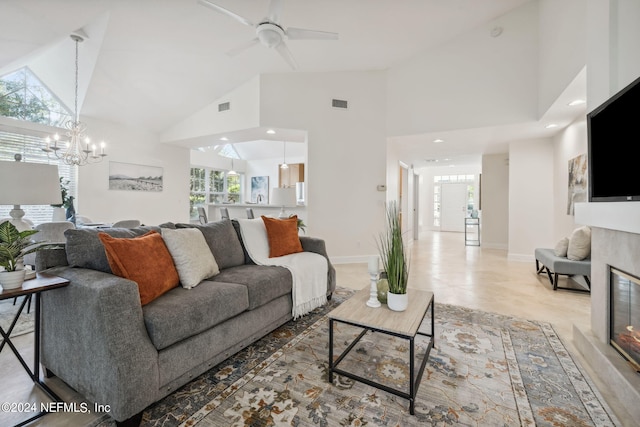 living room featuring ceiling fan with notable chandelier, a premium fireplace, and high vaulted ceiling