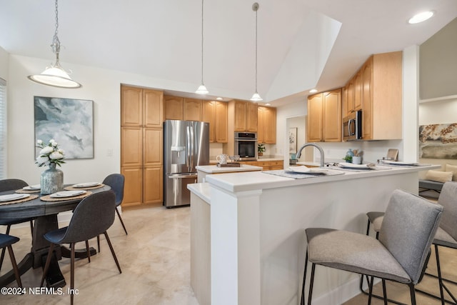 kitchen featuring lofted ceiling, kitchen peninsula, hanging light fixtures, a kitchen breakfast bar, and stainless steel appliances