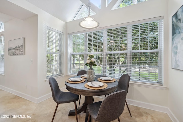 tiled dining space featuring vaulted ceiling and a healthy amount of sunlight