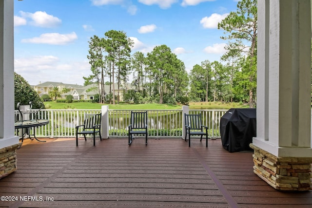 deck with a water view, grilling area, and a yard