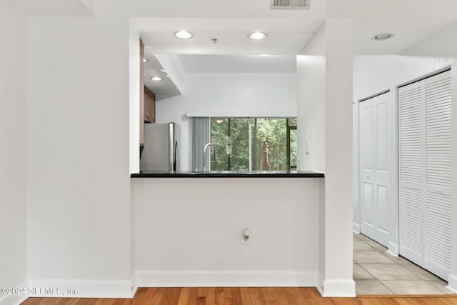 kitchen featuring ornamental molding, light wood-type flooring, sink, and stainless steel fridge