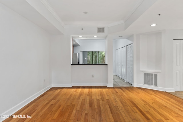 spare room with light wood-type flooring and ornamental molding