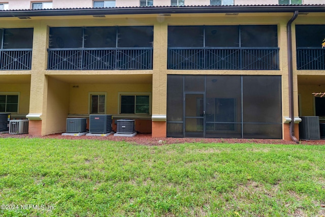 rear view of house with central air condition unit and a yard