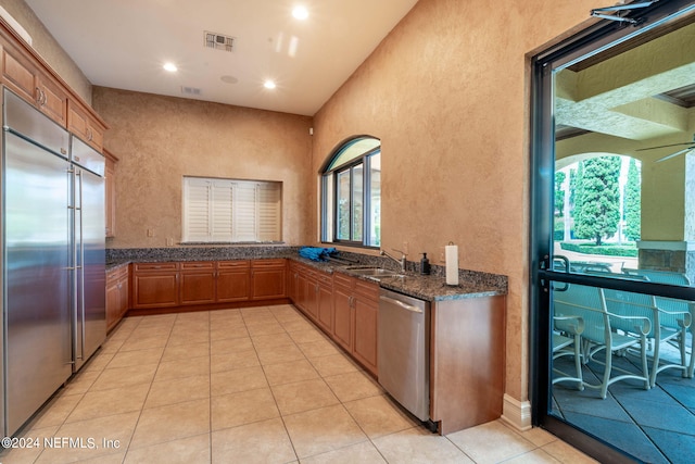 kitchen featuring ceiling fan, appliances with stainless steel finishes, plenty of natural light, and dark stone countertops