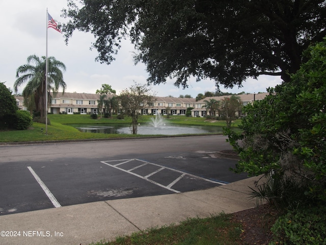 view of parking / parking lot featuring a lawn and a water view