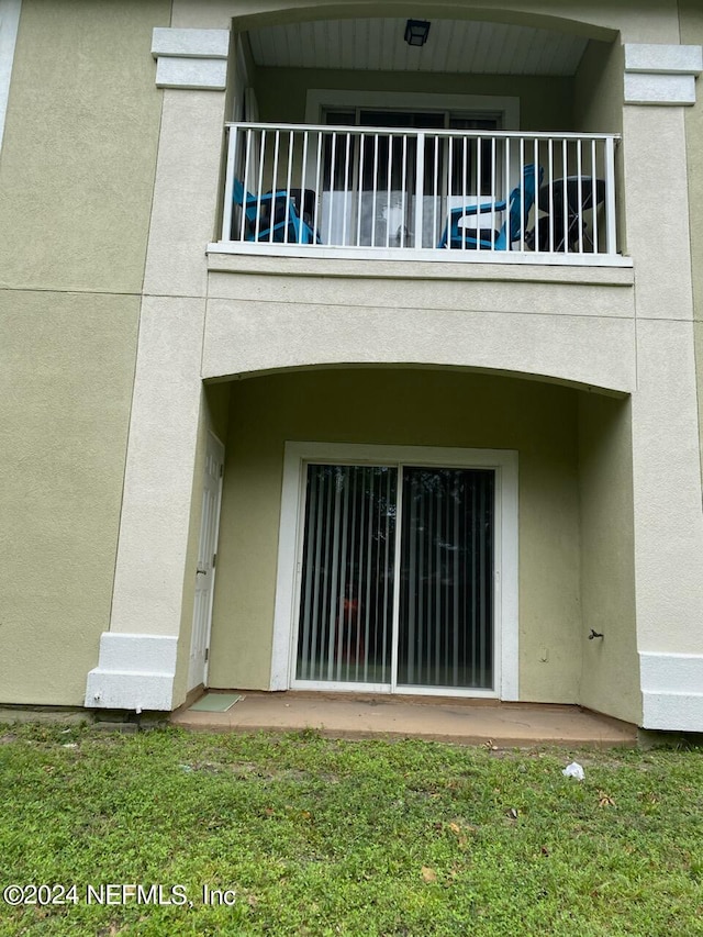 back of house featuring a yard and a balcony