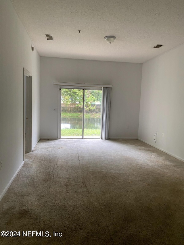 carpeted spare room featuring a textured ceiling