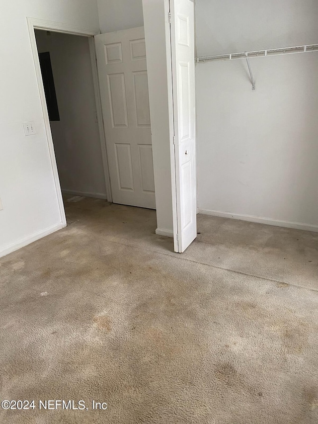 unfurnished bedroom with a closet and light colored carpet