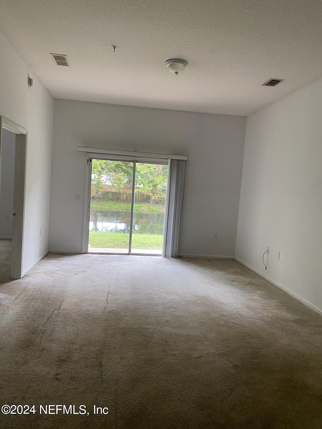 carpeted spare room featuring a textured ceiling