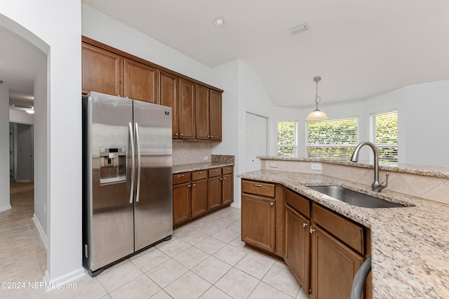 kitchen with light stone countertops, sink, stainless steel fridge, decorative light fixtures, and light tile patterned floors