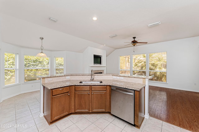 kitchen with a kitchen island with sink, a healthy amount of sunlight, stainless steel dishwasher, and light wood-type flooring