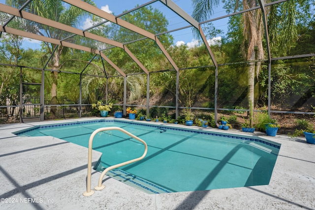 view of pool with glass enclosure and a patio area