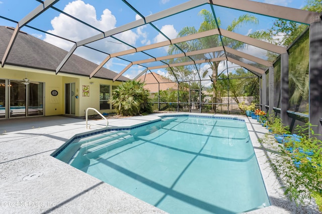 view of pool with glass enclosure and a patio area