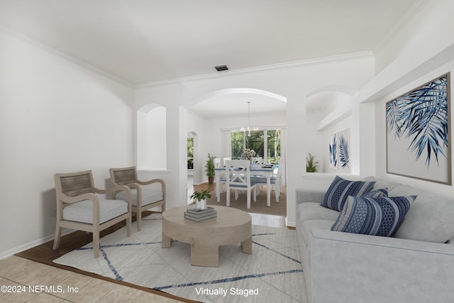 living room featuring ornamental molding, light hardwood / wood-style flooring, and an inviting chandelier