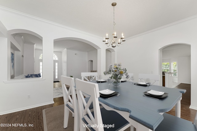 dining space featuring dark hardwood / wood-style flooring, an inviting chandelier, and ornamental molding