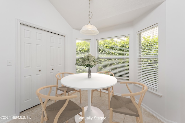 dining space with light tile patterned floors and vaulted ceiling