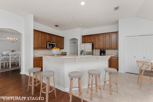 kitchen with decorative backsplash, a center island, stainless steel appliances, and light wood-type flooring