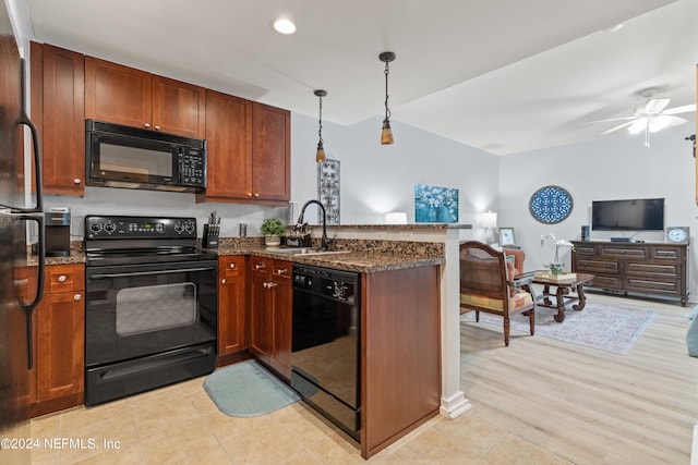 kitchen featuring hanging light fixtures, kitchen peninsula, light wood-type flooring, black appliances, and sink