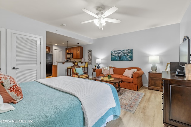 bedroom with light hardwood / wood-style flooring, ceiling fan, and black refrigerator