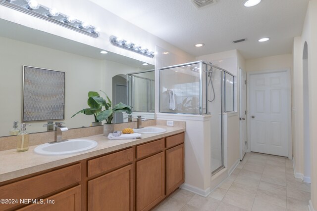 bathroom with a textured ceiling, tile patterned flooring, vanity, and an enclosed shower