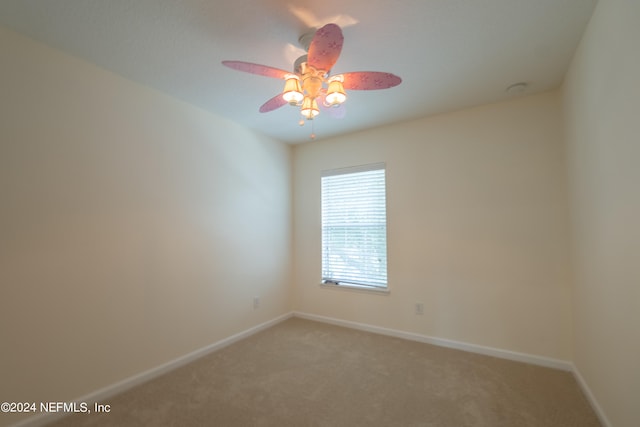 empty room featuring ceiling fan and carpet