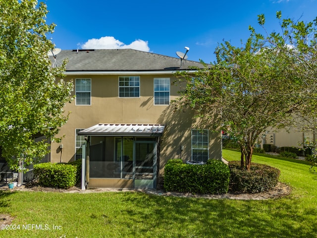 rear view of property with a sunroom and a lawn