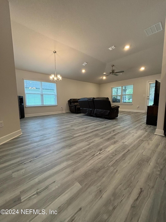 living room with a healthy amount of sunlight, vaulted ceiling, ceiling fan with notable chandelier, and hardwood / wood-style flooring