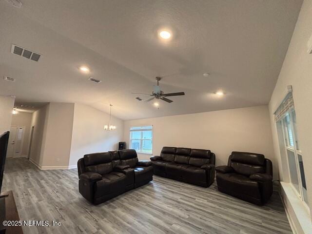 living room featuring ceiling fan with notable chandelier, hardwood / wood-style floors, and lofted ceiling