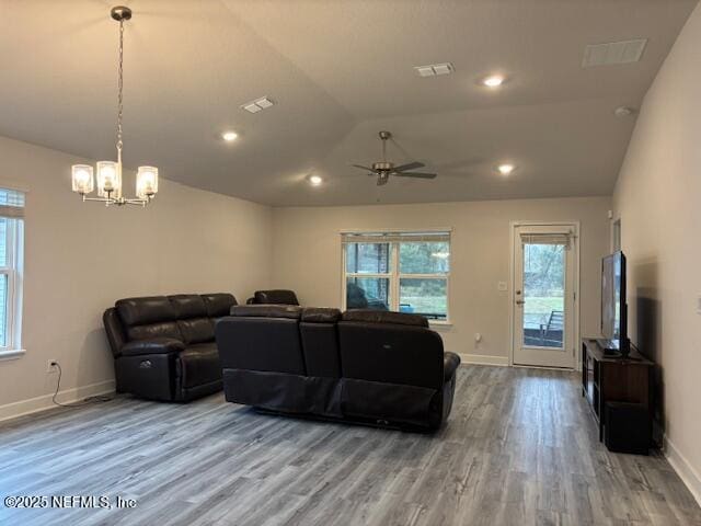 living room featuring ceiling fan with notable chandelier, wood-type flooring, and vaulted ceiling