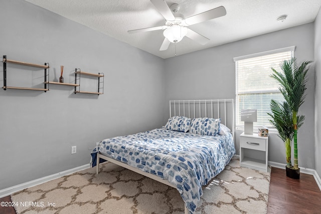 bedroom with a textured ceiling, dark hardwood / wood-style flooring, and ceiling fan