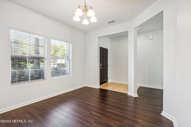 unfurnished room featuring hardwood / wood-style flooring and a chandelier