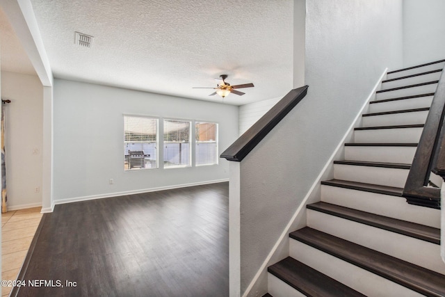 stairs featuring ceiling fan, hardwood / wood-style floors, and a textured ceiling