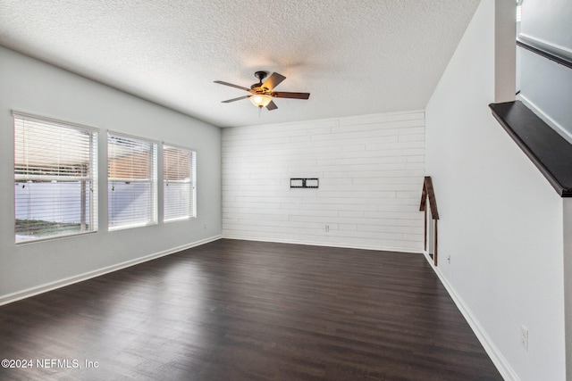 unfurnished living room featuring ceiling fan, a textured ceiling, brick wall, and dark wood-type flooring