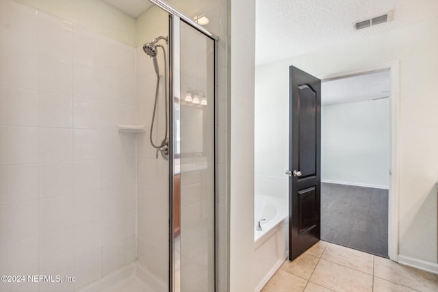 bathroom with a textured ceiling, tile patterned floors, and independent shower and bath