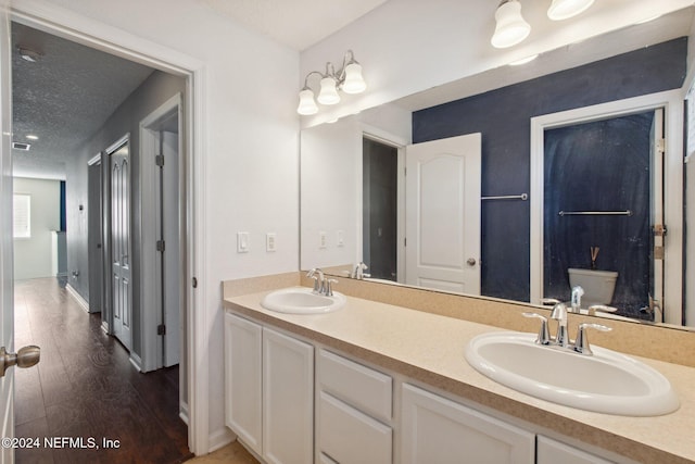 bathroom with vanity, toilet, wood-type flooring, and a textured ceiling