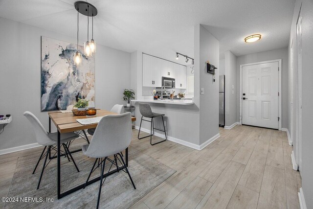 dining area featuring a textured ceiling and light hardwood / wood-style floors